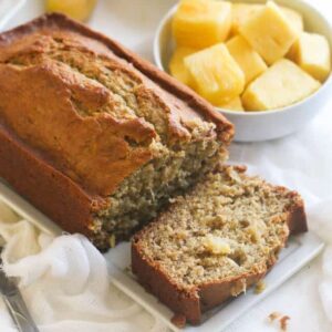 Banana pineapple bread with pineapple chunks and a banana in the background