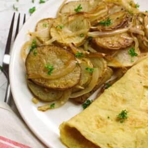 fried potatoes and onions with omelet on a plate