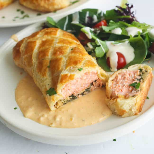 Salmon Wellington with cream sauce and a leafy green salad for an impressive dinner date