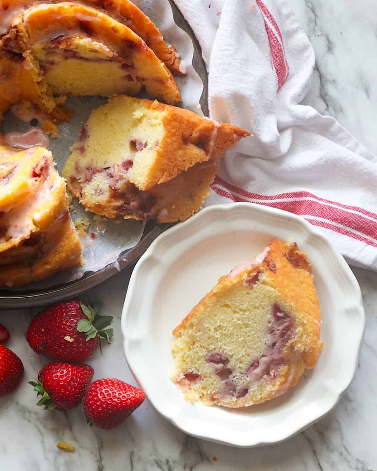 Serving up a slice of insanely good strawberry bundt cake with fresh strawberries on the side