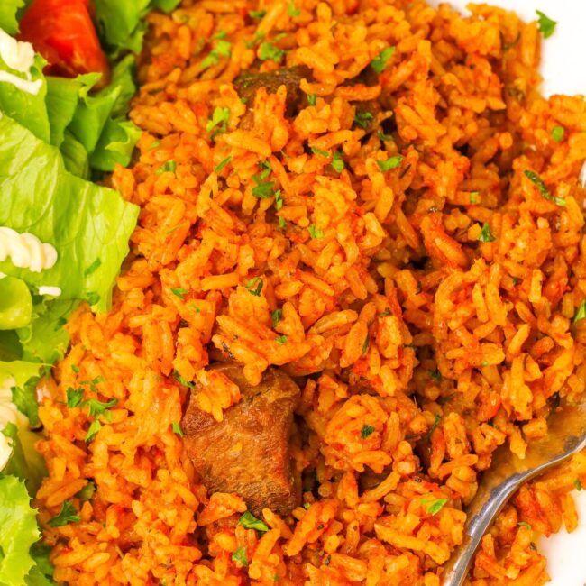 A delicious serving of Ghana jollof rice with a green salad for healthy soul food
