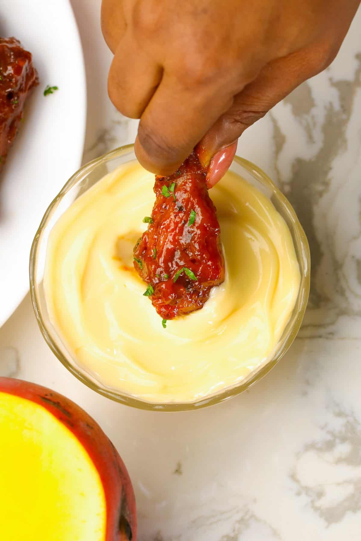 Dipping mango habanero wings in remoulade sauce to cool down the spice