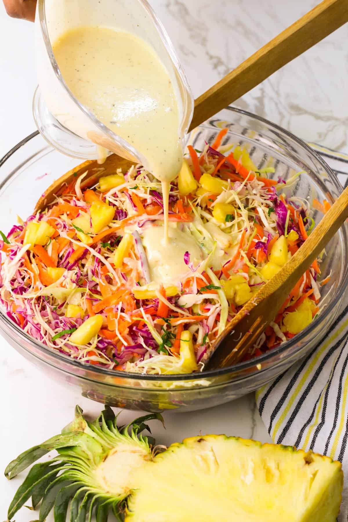 Adding the dressing to a gorgeous pineapple coleslaw