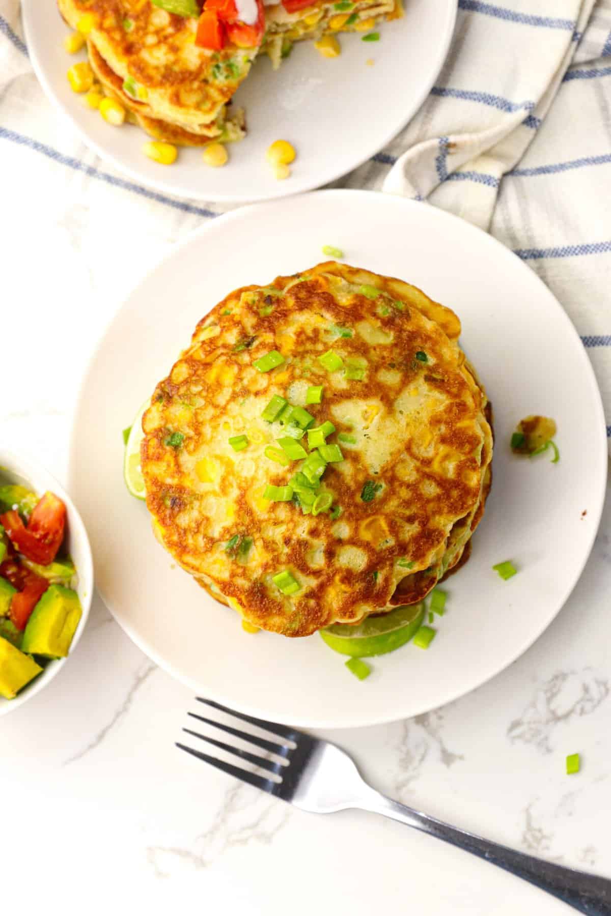 Getting ready to add toppings to a stack of savory, buttery, and slightly sweet corn cakes