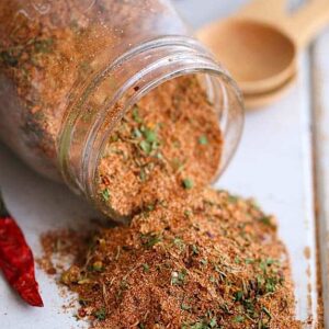 Spicy and flavorful Jamaican jerk seasoning spilling out of a glass jar