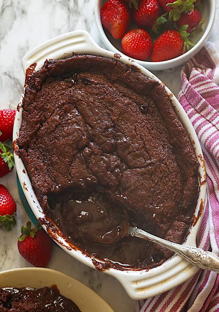 Serving up molten chocolate cobbler with fresh strawberries in the background