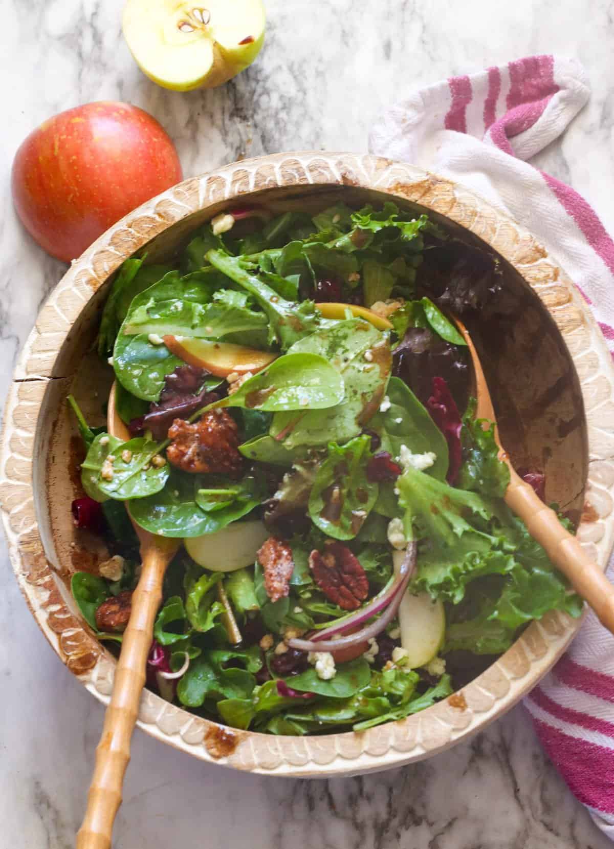 Tossing a freshly assembled apple pecan salad with the balsamic vinaigrette