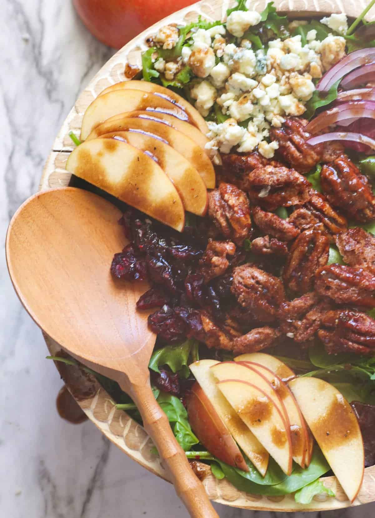 Drizzling the balsamic vinaigrette over a freshly assembled apple pecan salad