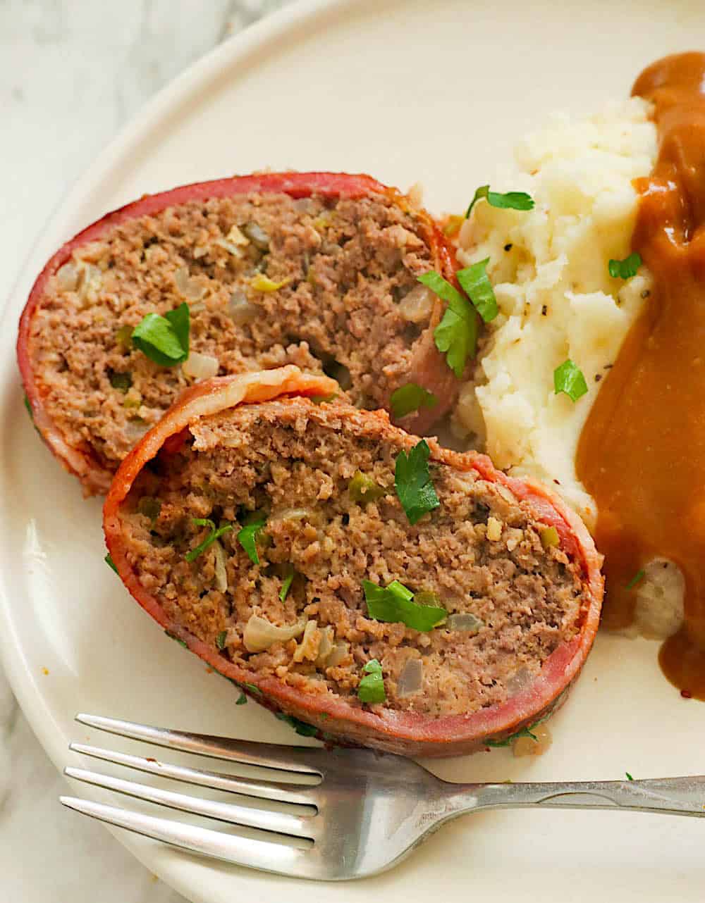 Enjoying two slices of bacon-wrapped meatloaf with mashed potatoes and gravy