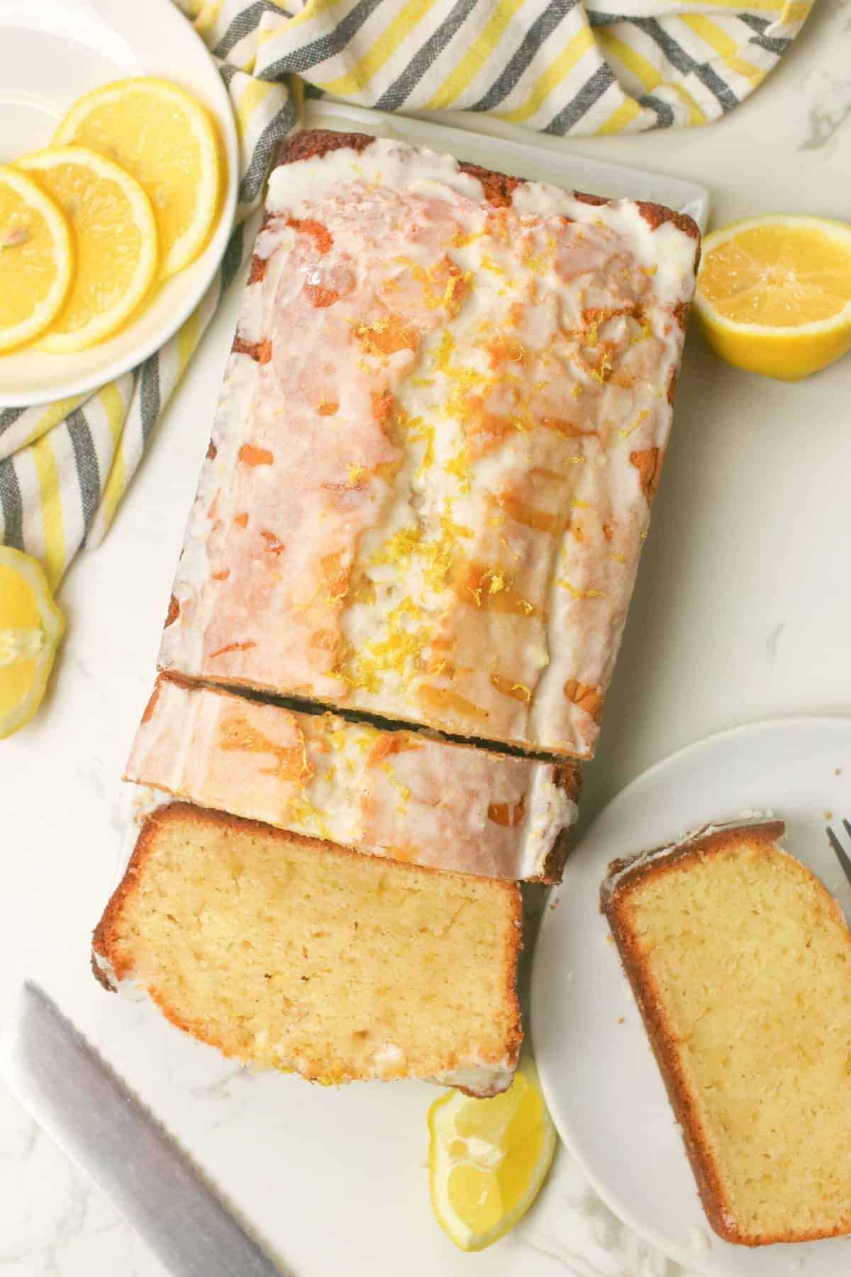 Slicing a loaf of freshly glazed lemon yogurt cake