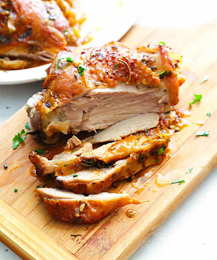 Slicing a juicy roasted turkey thigh on a wooden cutting board after its 10 minute resting period