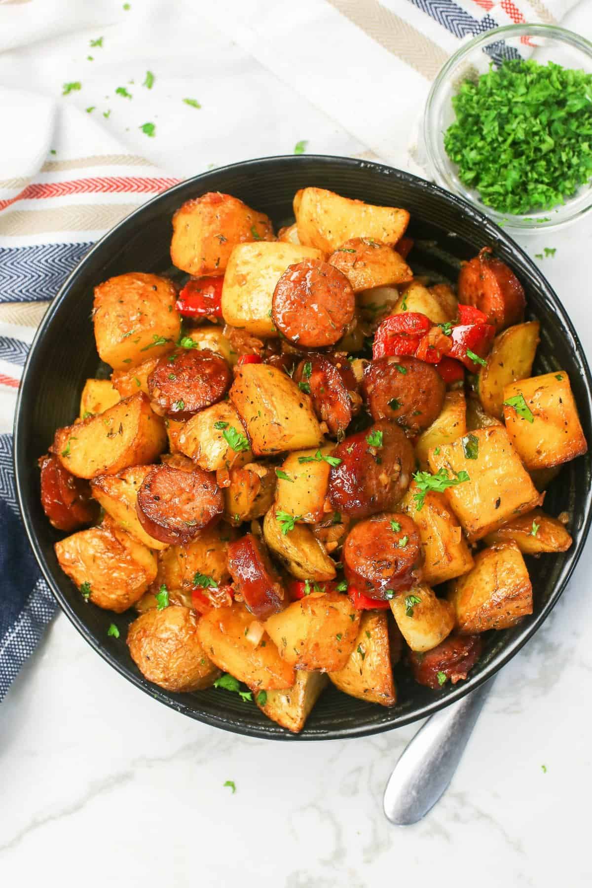 Serving up a black plate loaded with sausage and potatoes for comfort food deliciousness