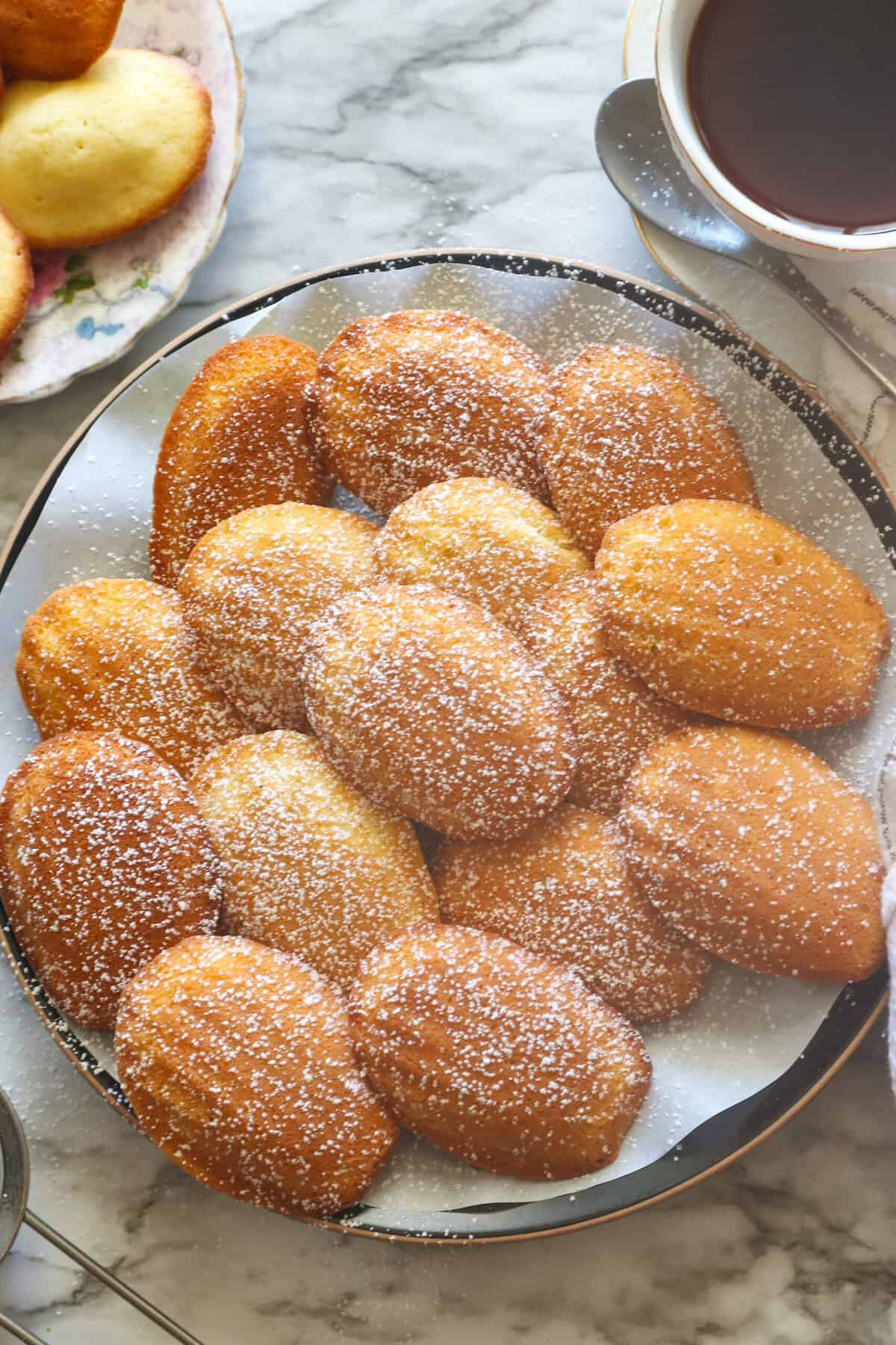 Freshly baked madeleine cookies dusted with powdered sugar ready to enjoy