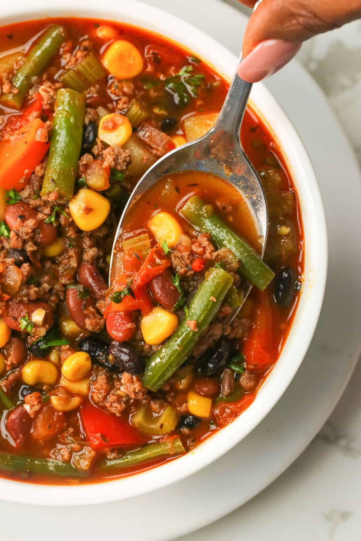 Enjoying a spoonful of insanely delicious and healthy vegetable soup with hamburger