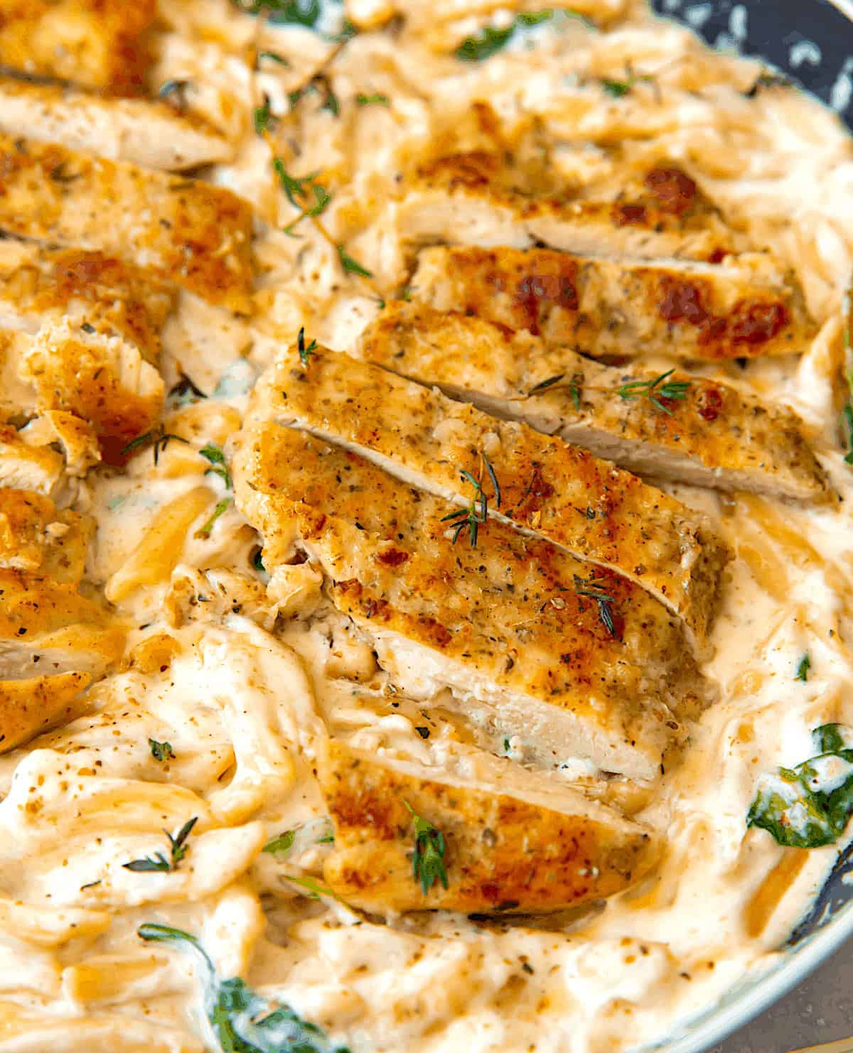 Provide seasoned chicken breasts with penne pasta and alfred sauce