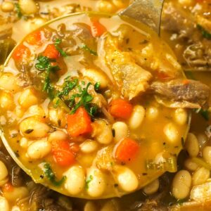 A healthy ladle full of navy bean soup with ham